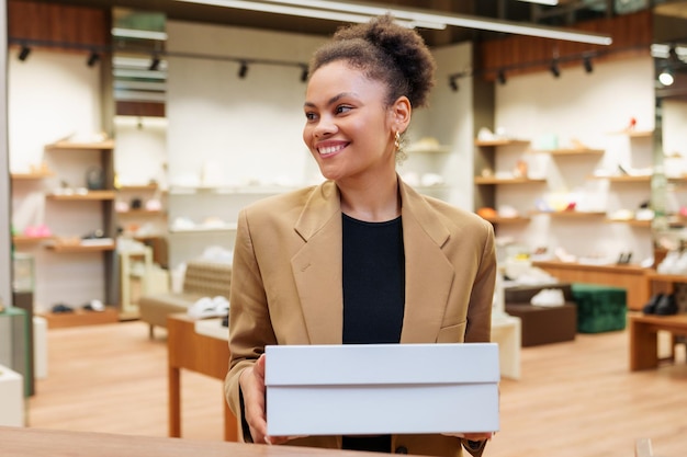 Uma mulher afro-americana com uma caixa de sapatos novos que ela comprou na loja