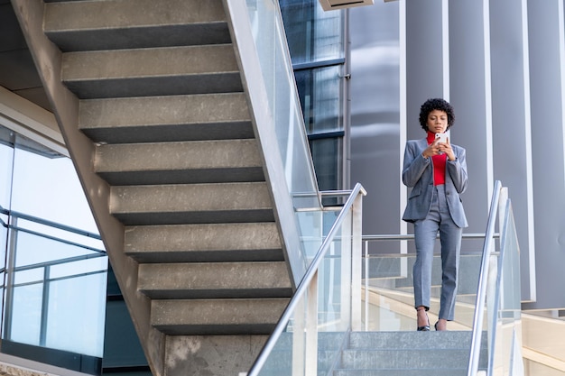 Foto uma mulher afro-americana elegante usando o telefone em um prédio de escritórios no trabalho