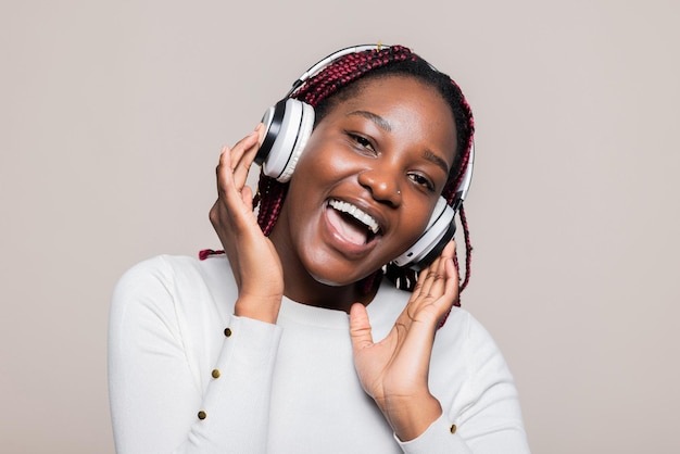 Uma mulher afro-americana sorridente, com tranças, a sorrir, a desfrutar das canções favoritas, a ouvir