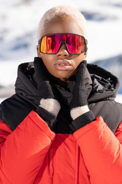 Uma mulher afro-americana usando óculos de neve em uma montanha de neve durante o inverno