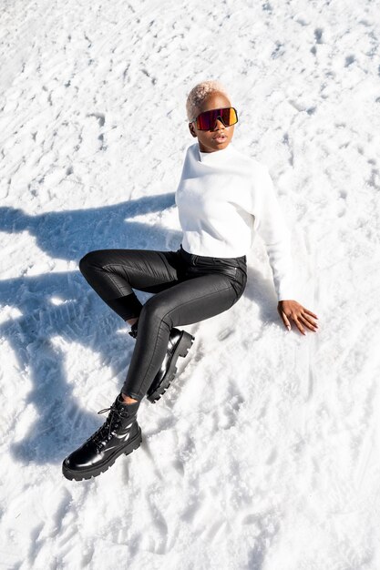 Uma mulher afro-americana usando óculos de neve em uma montanha de neve durante o inverno