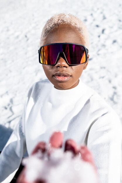 Uma mulher afro-americana usando óculos de neve em uma montanha de neve durante o inverno