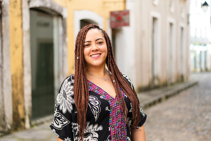 Foto uma mulher agachada em uma rua de paralelepípedos com tranças de cabelo e vestido africano pelourinho brasil