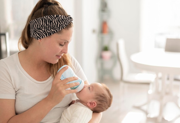 uma mulher alimentando o bebê recém-nascido com nutrição artificial de leite infantil. amor e carinho de mãe