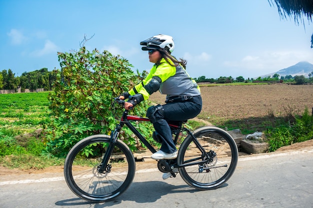 Uma mulher anda de bicicleta com um capacete.