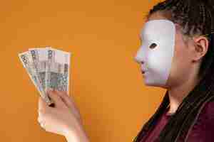Foto uma mulher anônima se levanta e puxa a mão com notas de papel com o valor nominal de cem zlotys poloneses sem rosto porque tem uma máscara.
