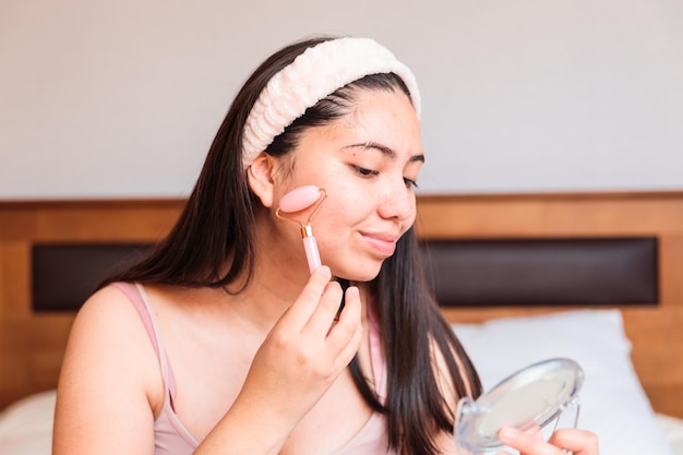 Uma mulher aplicando uma máscara facial no rosto.