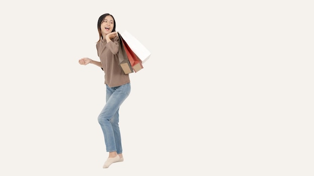 Uma mulher asiática alegre com suas sacolas de compras em pé contra um fundo branco isolado