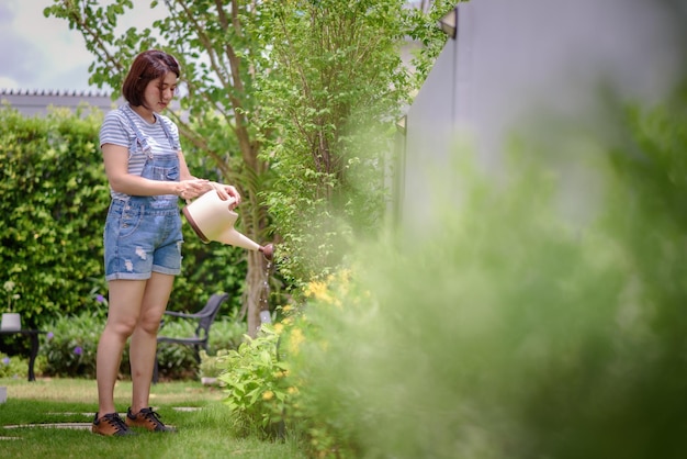 Uma mulher asiática está regando plantas no jardim