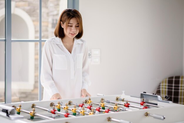 Uma mulher asiática jogando futebol futebol mesa jogo de tabuleiro Atividade de lazer e conceitos de entretenimento esportivo