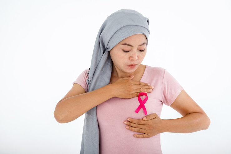 Foto uma mulher asiática usando lenço na cabeça com mão de fita rosa verificando nódulos em seu seio em busca de sinais de câncer de mama isolado no fundo do estúdio de cópia em branco branco, conceito de medicina