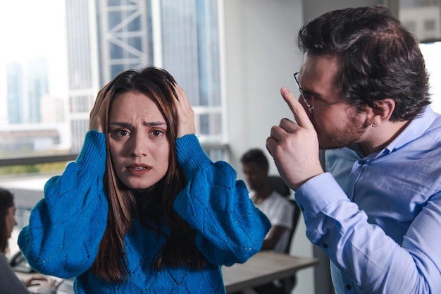 Uma mulher assustada está expondo a discriminação sexual por seu diretor homem em um escritório moderno