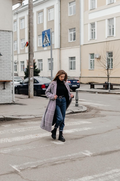 Uma mulher atravessando a rua de casaco e jeans