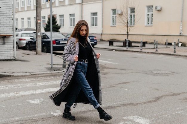 Uma mulher atravessando a rua de casaco e jeans