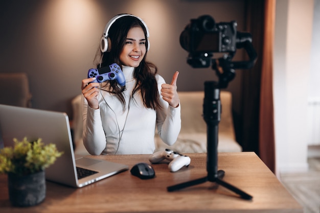 Foto uma mulher bonita blogueira com fones de ouvido está transmitindo ao vivo falando sobre videogames. jovem influente em transmissão ao vivo.