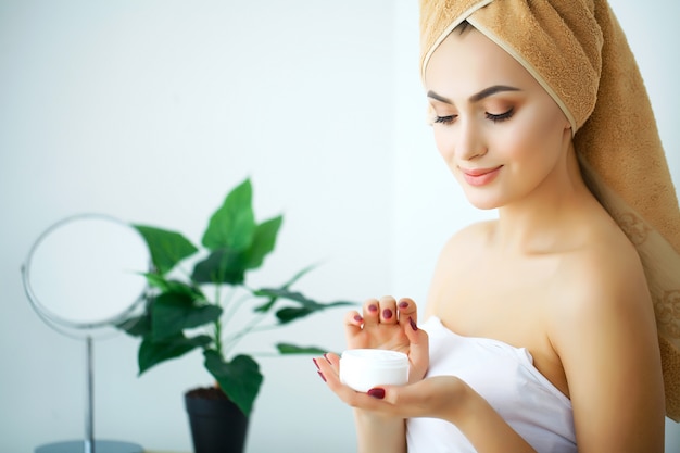 Uma mulher bonita usando um produto de cuidados da pele, hidratante ou loção e Skincare cuidando de sua pele seca. Creme hidratante nas mãos femininas