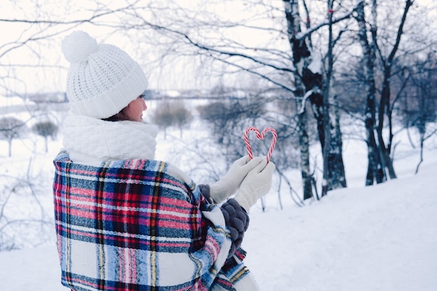 Foto uma mulher caminha pela floresta de inverno segurando bastões de doces nas mãos