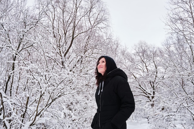 Foto uma mulher caminha sozinha em um parque coberto de neve entre árvores