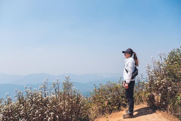 Uma mulher caminhando e de pé no topo de uma montanha olhando uma bela vista