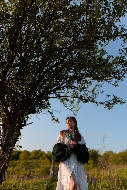 Foto uma mulher caminhando em torno de flores de lúpio e uma árvore em um parque