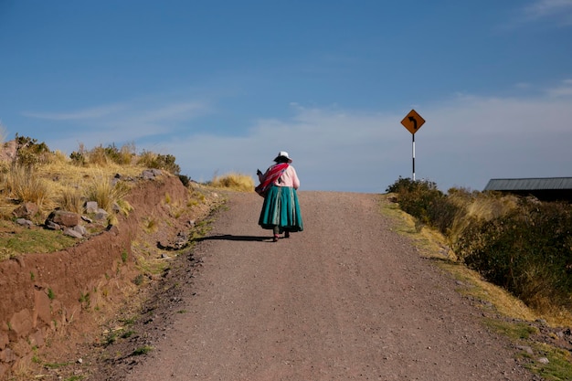 Uma mulher caminhando por um caminho em Llachon perto do Lago Titicaca no Peru