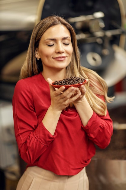 Foto uma mulher cheirando grãos de café torrados em uma fábrica de café