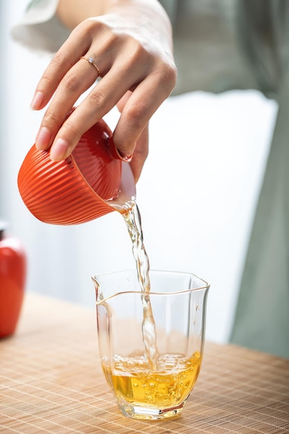 Uma mulher coloca um copo de chá de laranja em um copo.
