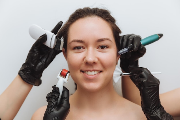 Uma mulher com as mãos de vários terapeutas com dispositivos de cosmetologia perto de seu rosto uma mulher precisa de cuidados com a pele foto do conceito de cuidados com a pele