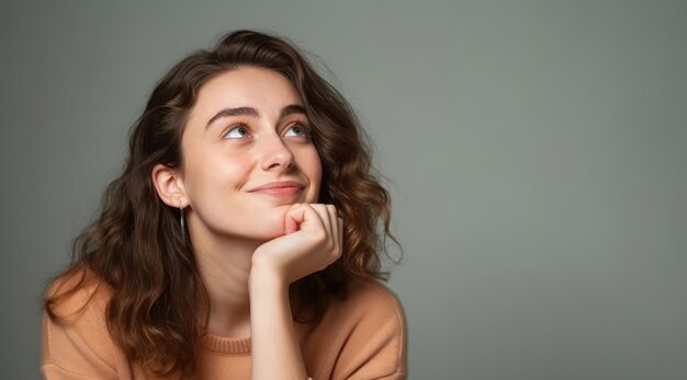 Uma mulher com cabelo castanho e um suéter marrom olha para cima e sorri.