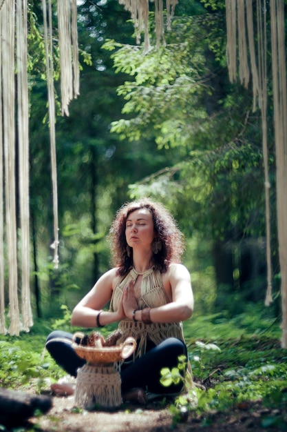 Uma mulher com cabelo encaracolado escuro vestida como um nativo medita na floresta