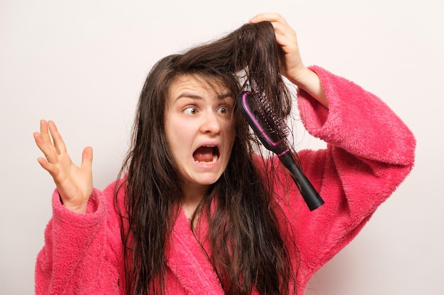 Uma mulher com cabelo longo e emaranhado molhado tenta pentear