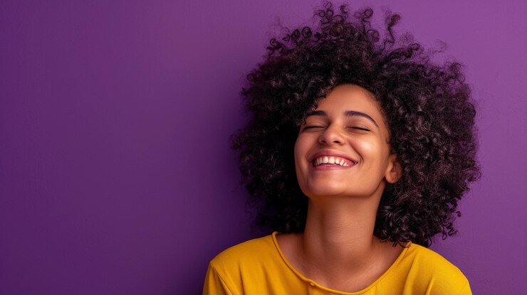 Foto uma mulher com cabelos encaracolados sorri contra um fundo roxo