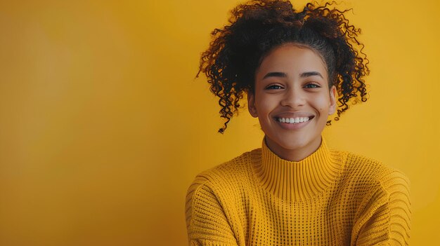 Uma mulher com cabelos encaracolados sorrindo e vestindo um suéter amarelo e sorrindo para a câmera com um amarelo