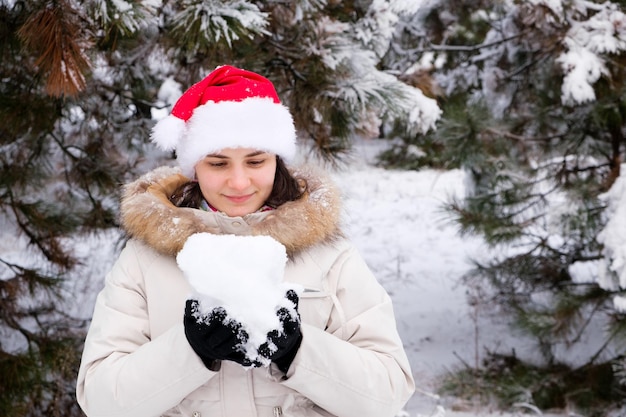 Uma mulher com chapéu de Papai Noel tem uma bola de neve nas mãos