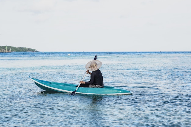 Uma mulher com chapéu de verão brincando de caiaque ou bote no oceano na Ilha Karimun Jawa