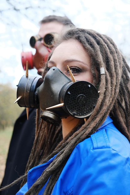 Uma mulher com dreadlocks e uma máscara de gás e um homem com óculos steampunk e uma máscara de gás
