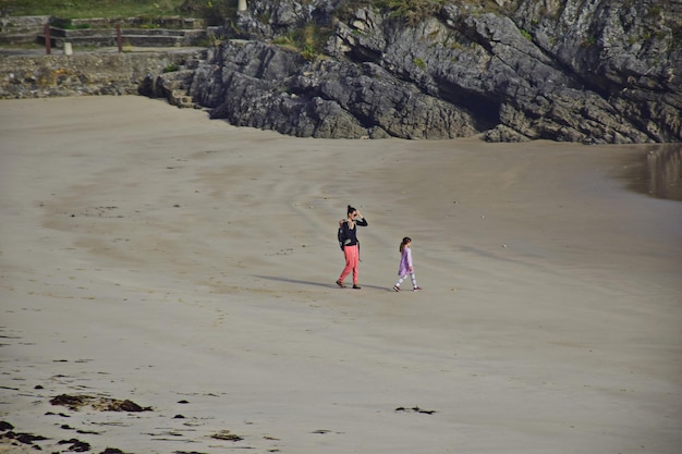 Uma mulher com filhos caminha ao longo da praia até a água o caminho de st james rota do norte espanha