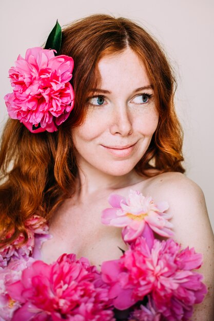 Uma mulher com flor de peônia no cabelo dela.