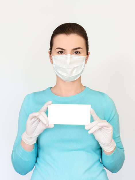 Uma mulher com máscara médica e luvas cirúrgicas segura um pequeno tablet com lugar para texto
