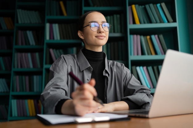 Uma mulher com óculos é uma gerente trabalhando em um escritório usando um laptop concept office