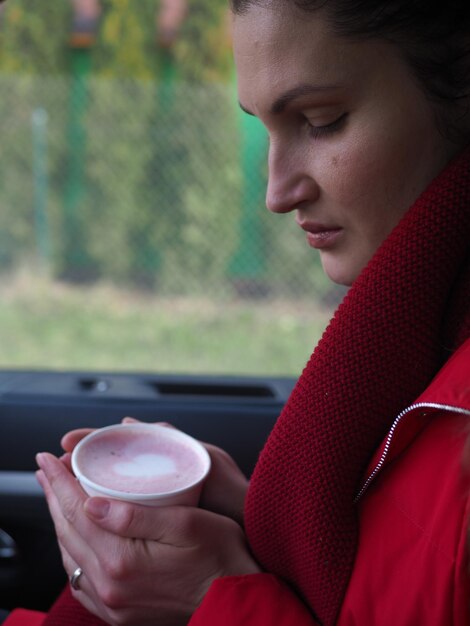 Uma mulher com os olhos fechados e os olhos fechados, segurando uma xícara de chocolate quente.