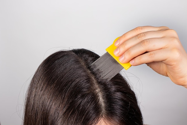 Uma mulher com pediculose limpa o cabelo de piolhos e lêndeas