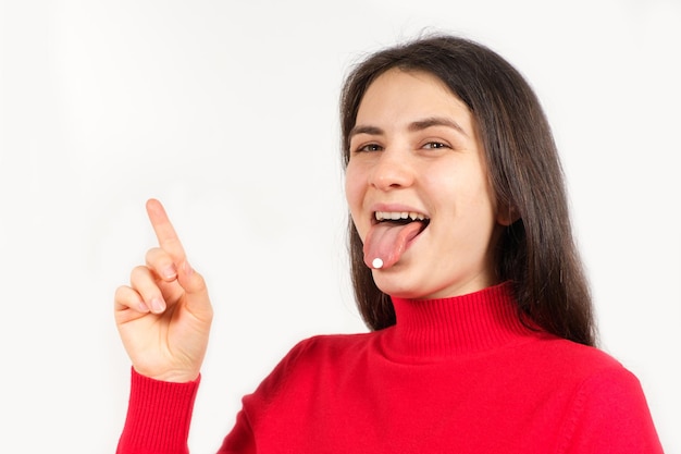 Uma mulher com pílulas na língua aponta o dedo para um lugar para texto