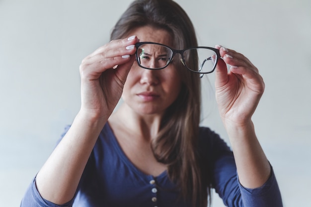 Uma mulher com problemas de visão enxerga mal através dos óculos