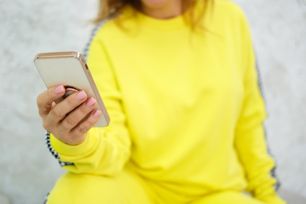 Uma mulher com um agasalho amarelo segura um celular nas mãos o conceito de dois futuros padrões móveis 5g e 6g