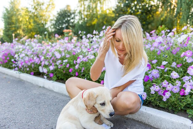 uma mulher com um cachorro na frente de um jardim de flores