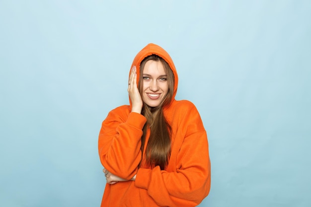 uma mulher com um capuz laranja com as mãos no rosto