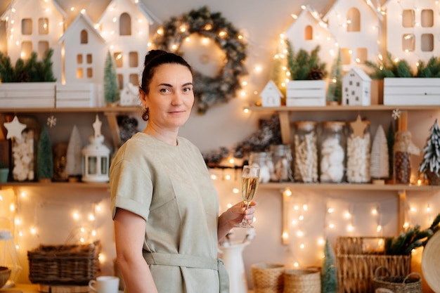 Uma mulher com um copo na cozinha decorada de ano novo