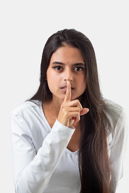 Uma mulher com um dedo na boca está dizendo silêncio.