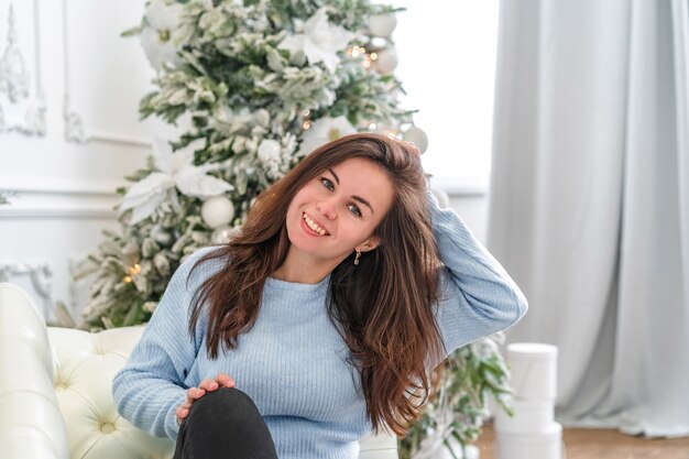 Uma mulher com um suéter aconchegante em frente a uma árvore de Natal decorada, um conceito festivo